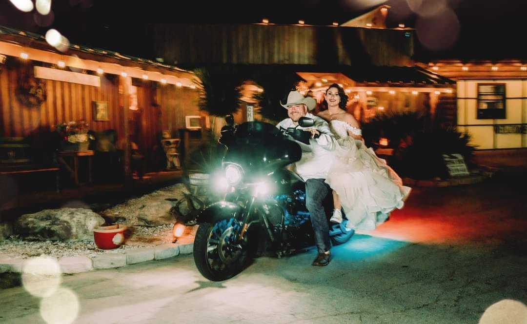 Newly married couple leaving on a motorcycle after their reception